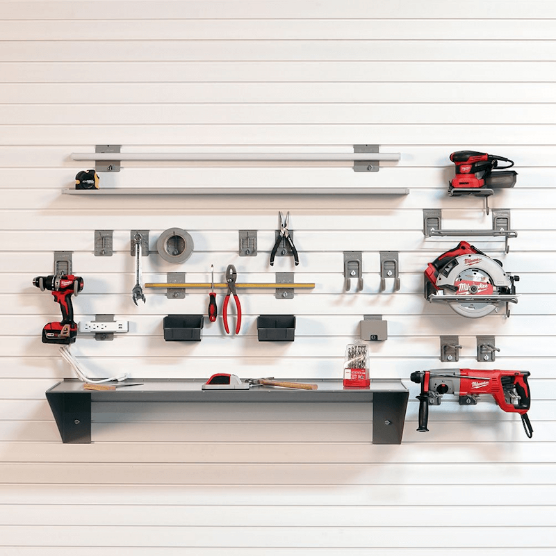 StoreWALL white slatwall panel system loaded with Milwaukee power tools, hand tools, drill bits, and a steel shelf -- showing hooks, bins, and accessories organized across the full wall