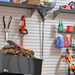Garage slatwall with racks and hooks from the front with hooks holding clippers, rakes and more.