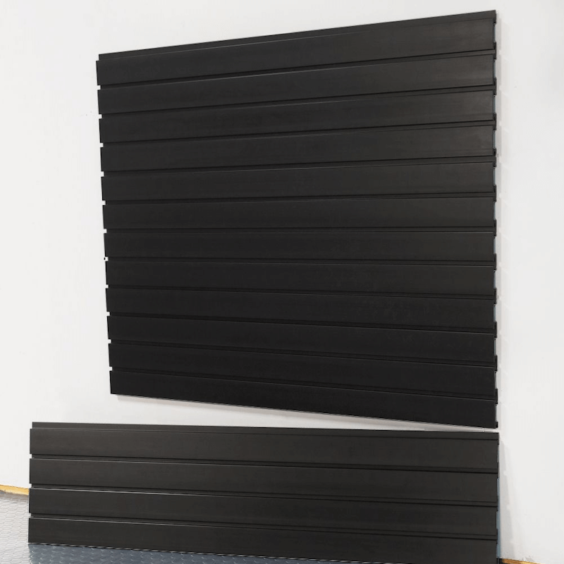 Black standard duty slatwall panels installed on a garage wall, showing sleek interlocking design and smooth matte finish by Oura Decor.