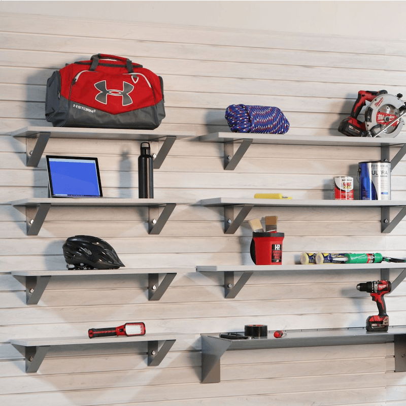 Whitewood slatwall panels with mounted metal shelves holding garage tools, gear, and accessories, showcasing Oura Decor’s organized storage system.