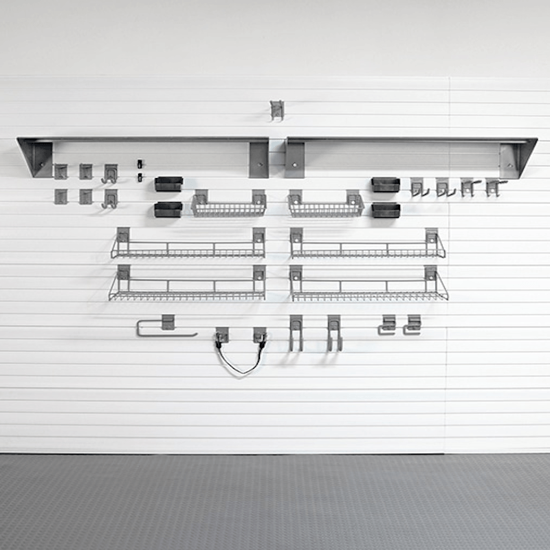A set of gray metal wire kitchen shelves and hooks mounted on a white slatted garage door, with a gray floor visible below.