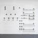 A set of silver metal wire shelving and wall-mounted brackets arranged in a grid pattern on a white paneled wall.