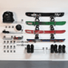 A wall-mounted snowboard storage rack holding multiple snowboards, snow boots, a backpack, a helmet, and goggles on a white slatwall in a garage-like setting.