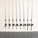 Eight fishing rods with different colored lines and black spincast reels mounted on a white slatwall.