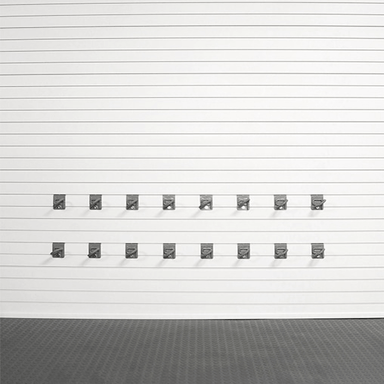 A set of twelve dark gray metal garage door hooks arranged in two rows of six on a white slatted garage door, with a dark textured floor below.