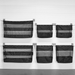 Set of six black mesh storage bags hanging on a white wall.