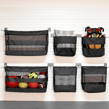 Six black mesh and fabric hanging storage pockets mounted on a white paneled wall, shown empty and filled with assorted sports balls and gear to demonstrate storage capacity.