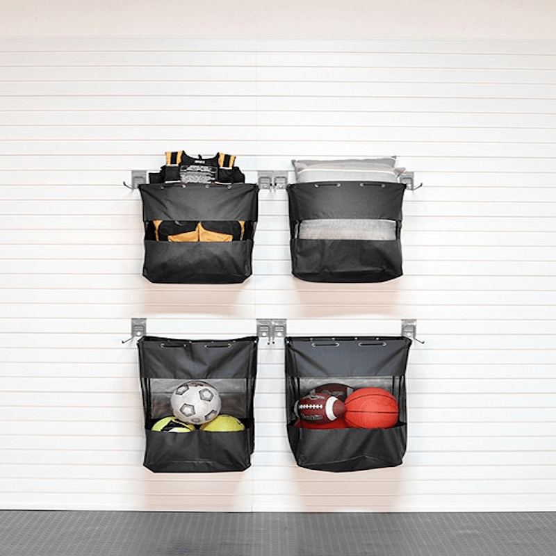 Four black wall-mounted storage bags with sports balls on a white wall.