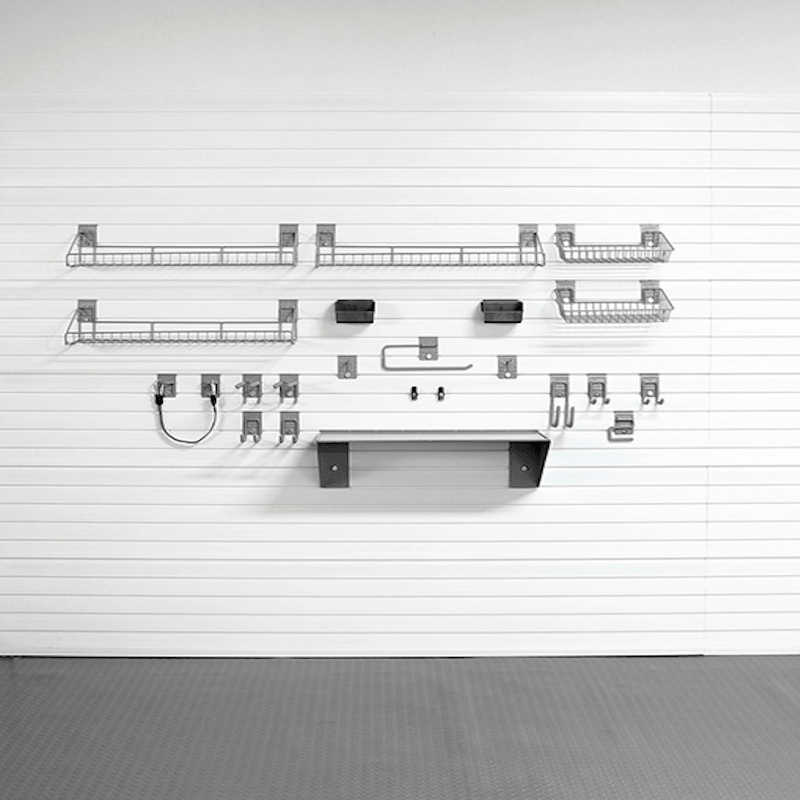 A set of wall-mounted metal storage shelves and hooks arranged on a white paneled wall above a gray floor.