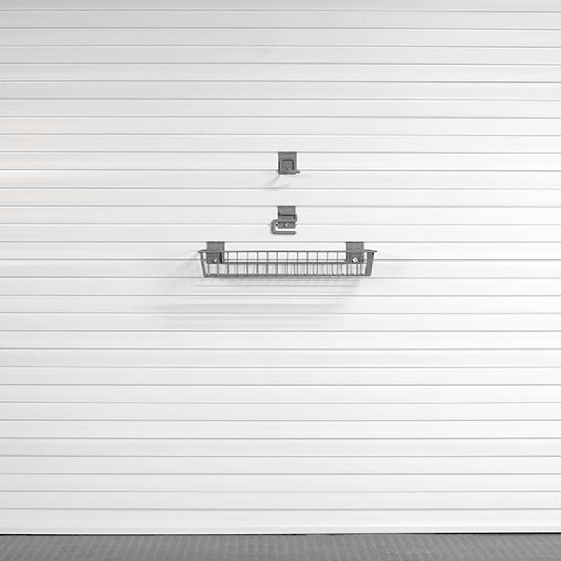 A gray metal wire basket shelf with two matching wall brackets, mounted on a white horizontally paneled garage door.
