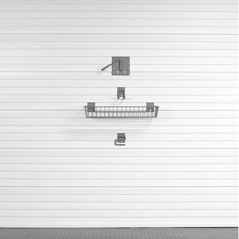 A set of dark gray metal garage door hardware and a wire basket shelf mounted on a white slatted garage door.