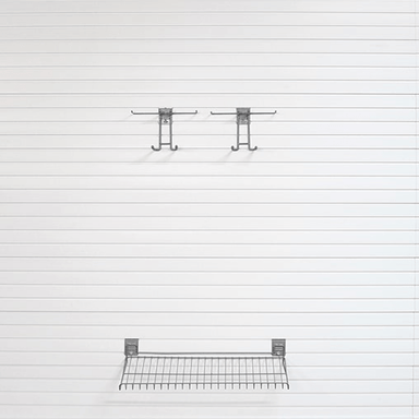 A wall-mounted metal wire shelf and two matching hanging hooks on a white paneled wall.
