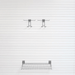 A wall-mounted metal wire shelf and two matching hanging hooks on a white paneled wall.