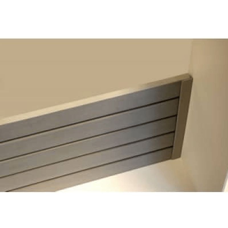 A close-up of a gray slatted panel or door stopper mounted against a beige wall in an indoor setting.