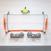 A wall-mounted basketball hoop set with orange side panels labeled BOWNET, a white net, two metal ball racks filled with soccer balls, and a yellow cone on a white paneled wall.
